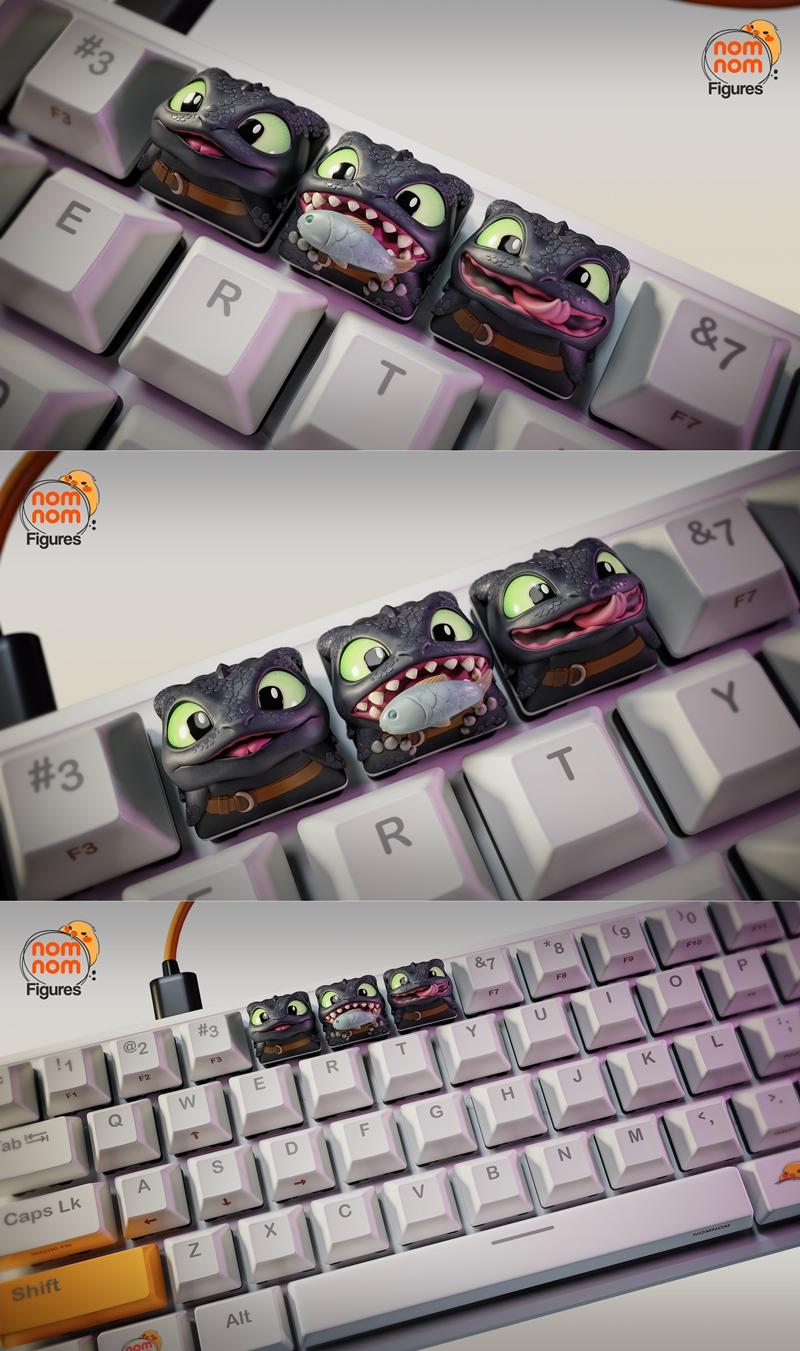 Three Toothless dragon keycaps on a white mechanical keyboard. One keycap shows Toothless with a fish in its mouth, a...