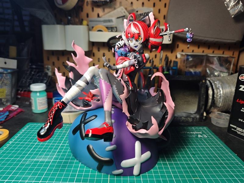 Kureiji Ollie 3D model figure, seated on a large blue and purple abstract base, holding a sword. She has red and whit...
