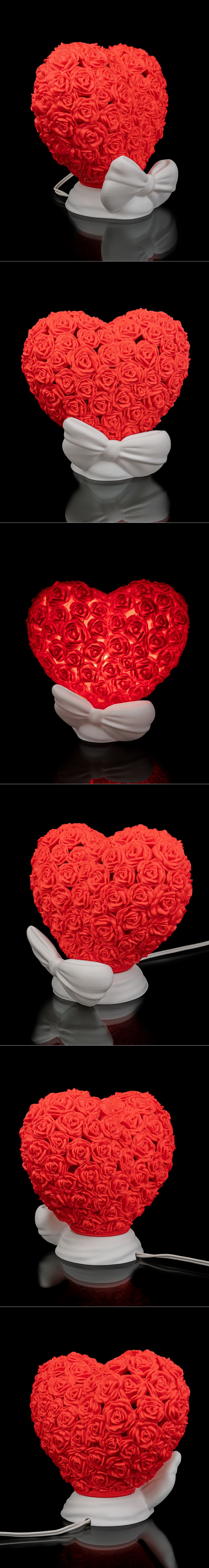 Heart-shaped table lamp covered in red roses, with a white bow-shaped base, illuminated from within.