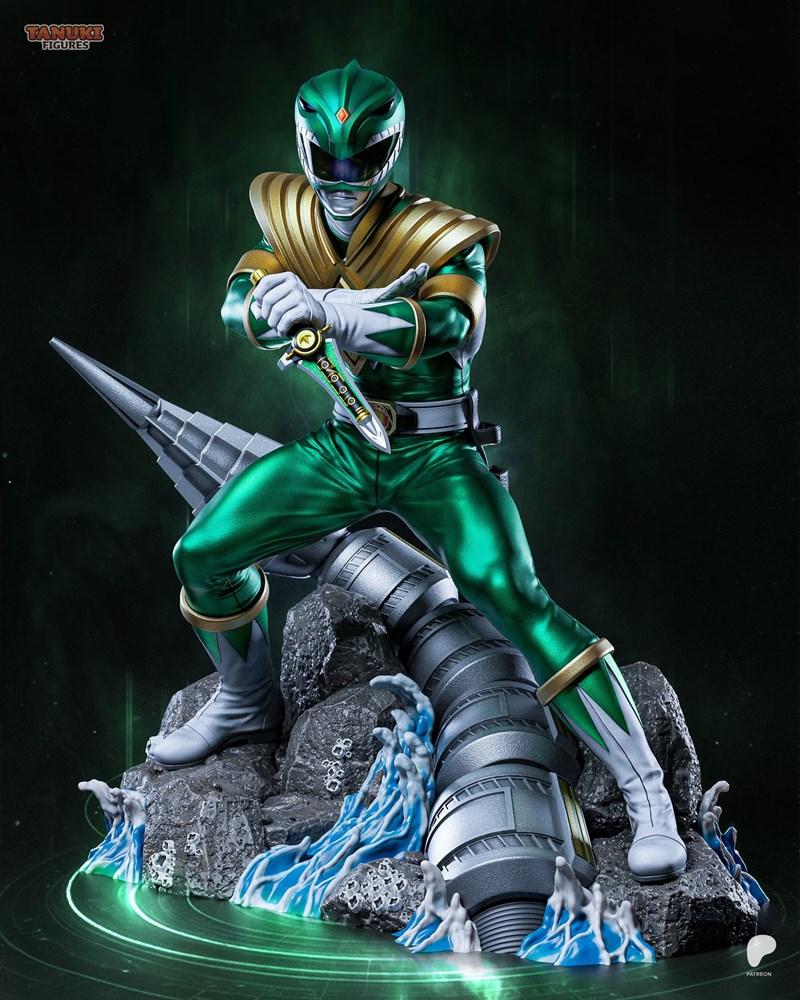 Green Ranger figure from Power Rangers, holding a dagger, in a heroic pose on a rocky diorama with blue water effects...