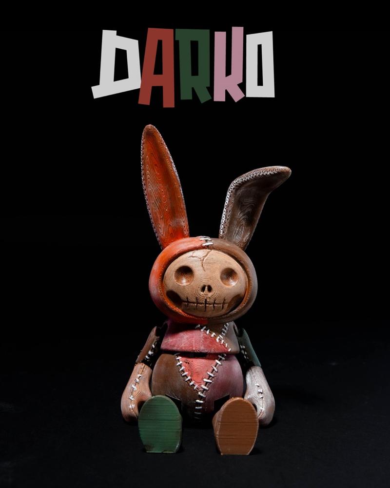Articulated creepy bunny figure named Darko, with a skull face, stitched seams, and mismatched colored limbs, sitting...