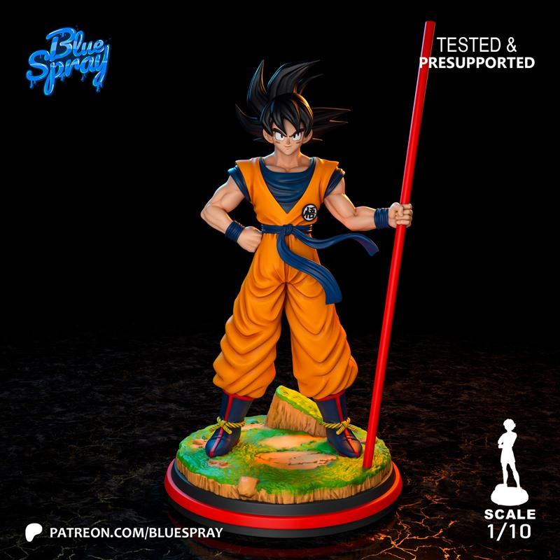 Young Goku figure in orange gi holding a red staff, standing on a scenic base. Blue Spray studio logo visible. Scale...