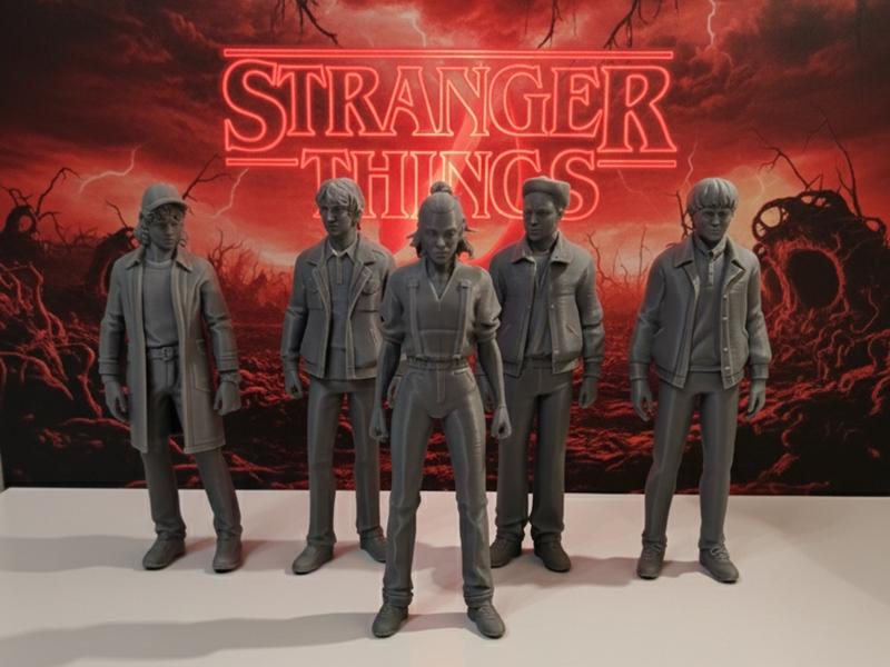 Five 3D printed figures of Stranger Things characters standing in a line, with the Stranger Things logo in the backgr...