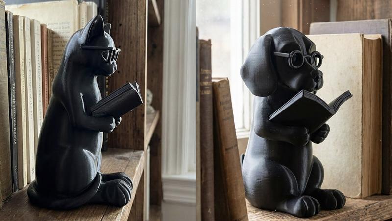 Black 3D printed cat and dog figures wearing glasses and reading books, placed on a wooden shelf with antique books.
