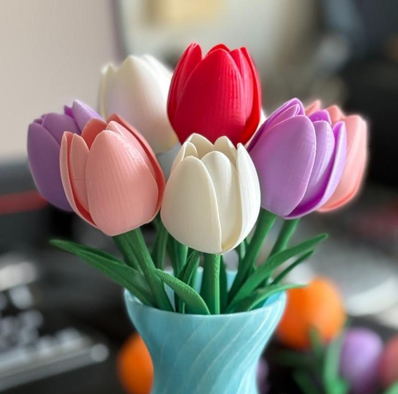 A bouquet of multi-colored 3D printed tulips in a blue vase, featuring red, white, pink, and purple blooms with green...