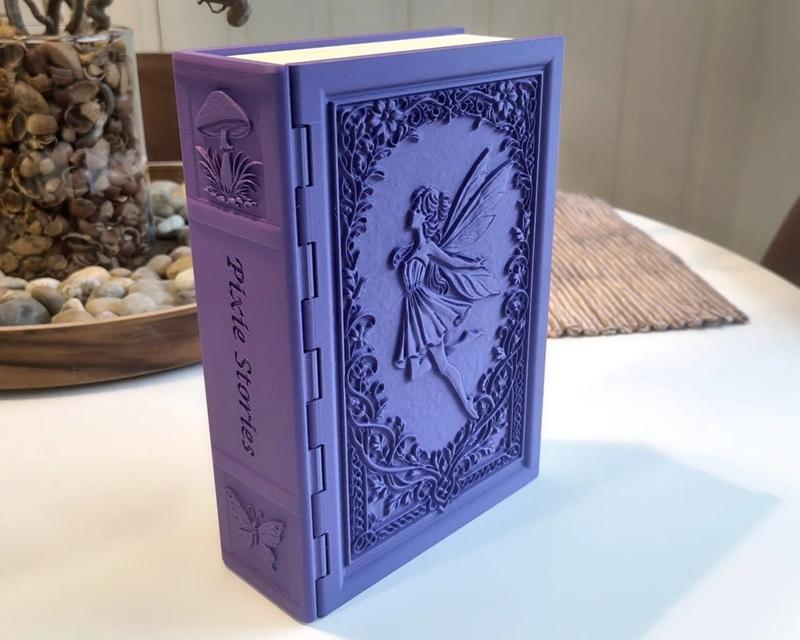 Purple 3D printed storage book designed to look like a fairy tale book, featuring a fairy on the cover and 'Pixie Sto...