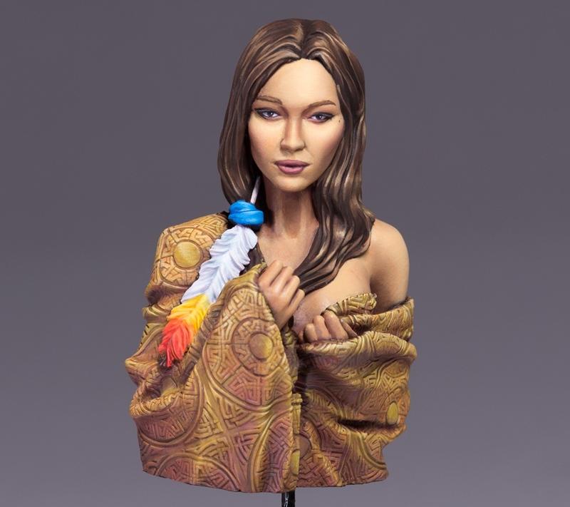 Bust of a woman with long brown hair, wearing a patterned golden cloth and a feather adornment. Ouroboros Miniatures...