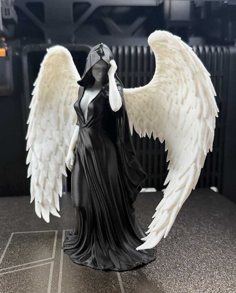3D printed figure of a hooded female angel with large white wings, wearing a flowing black gown.