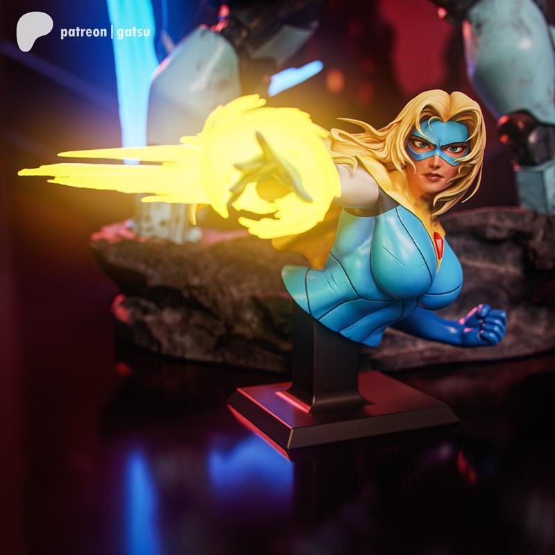 Bust of a blonde female superhero with a blue mask and costume, firing an energy blast from her right hand. Created b...